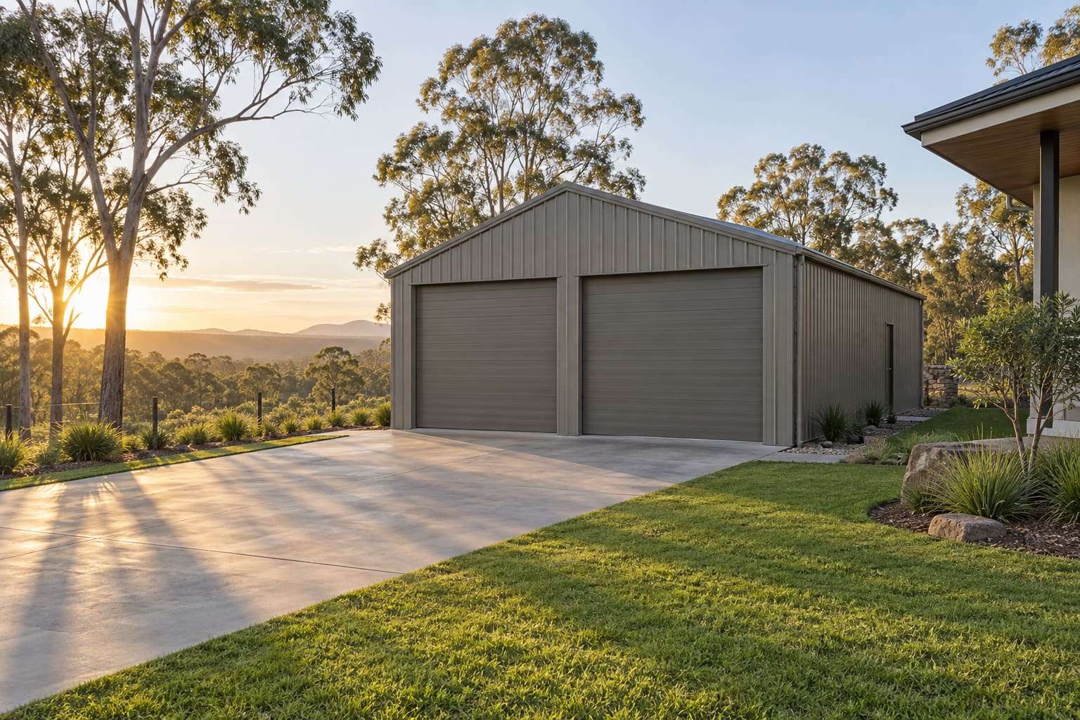 Freestanding steel double garage with two roller doors beside a concrete driveway on a Queensland acreage block